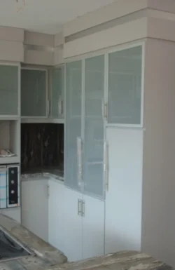 Cocina empotrada con laminado decorativo y perfiles metálicos Vista lejana de rincón derecho de módulos en lámina y perfiles metálicos